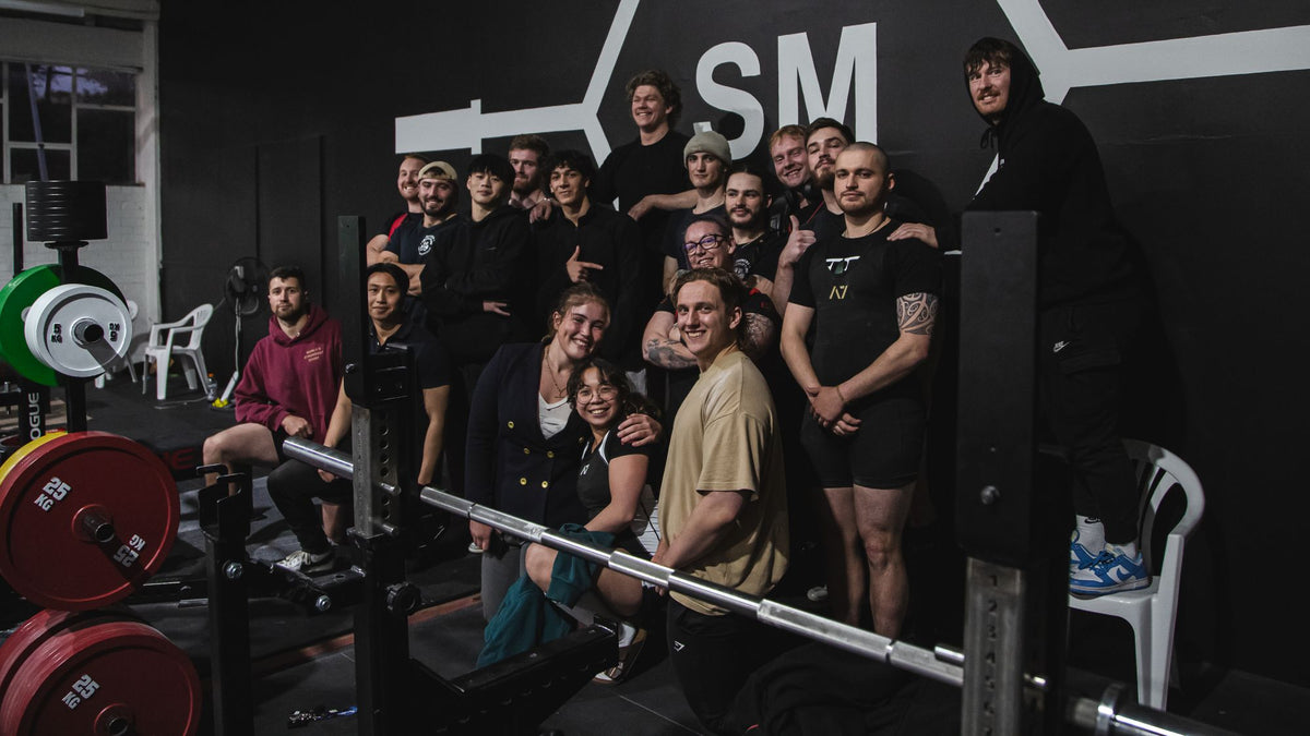 The Strength Metrics community in front of the gym's main wall